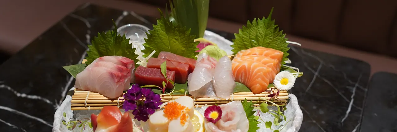 Sashimi of salmon, tuna and white fish with shiso leaves and flowers