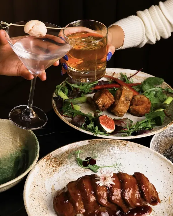 A table of Japanese dishes and cocktails raised in a toast