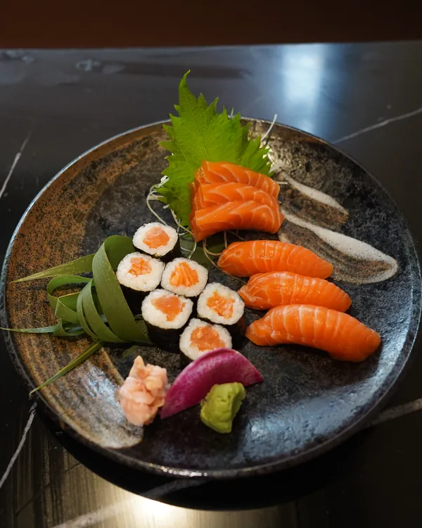 Salmon nigiri, salmon rolls and sashimi with ginger and wasabi on a stoneware plate