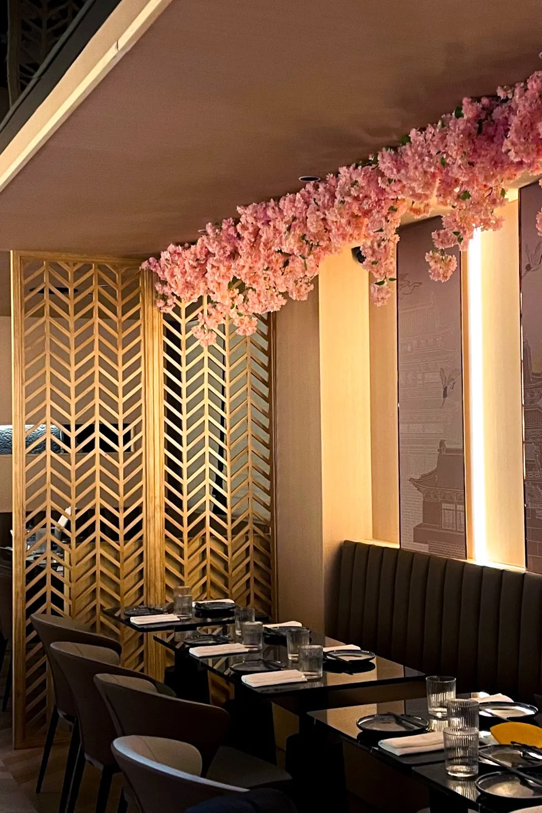The dining room under a canopy of pink blossom, beside a gold lattice screen
