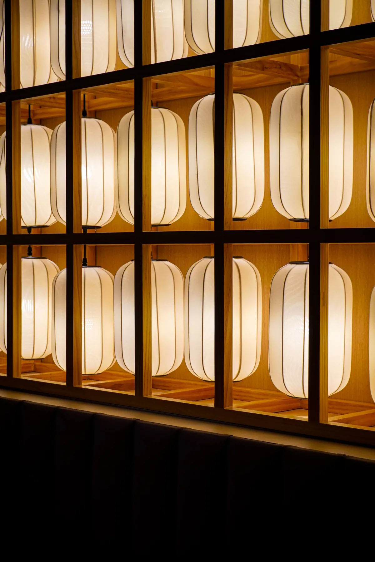 A wall of paper lanterns in a dark wooden lattice