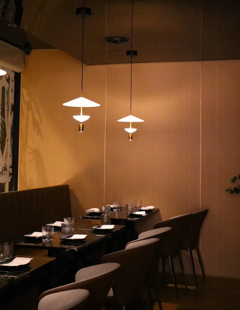 Tables laid for dinner under paper-shade pendant lights in Akatuki's dining room.